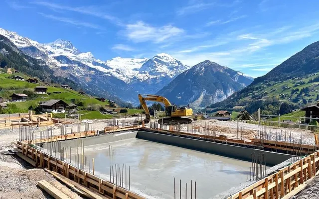 Chantier de construction d'une piscine en béton dans une vallée alpine du Valais