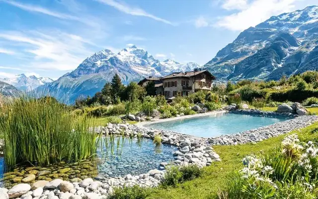 Piscine naturelle écologique avec zone de lagunage plantée de roseaux dans un jardin de villa alpine en Valais